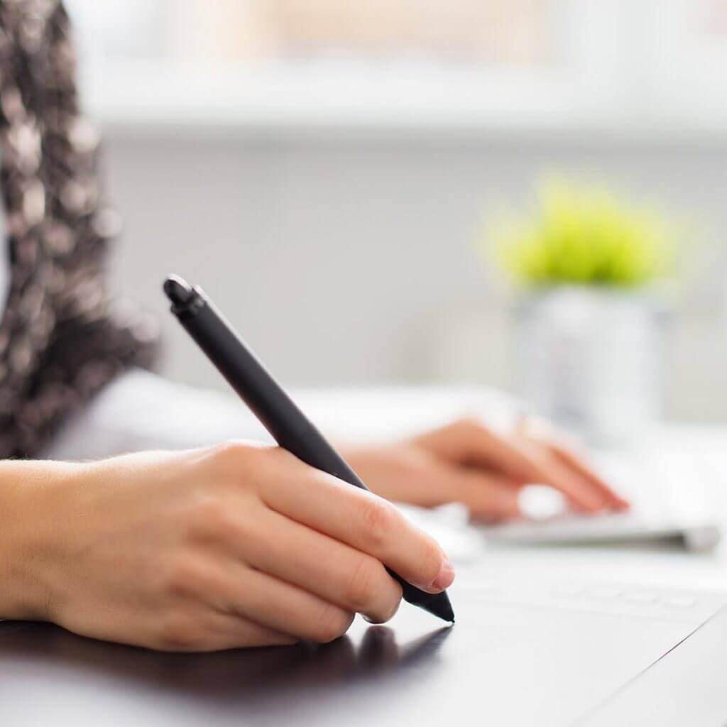 Eine Hand hält einen Stift und schreibt etwas.